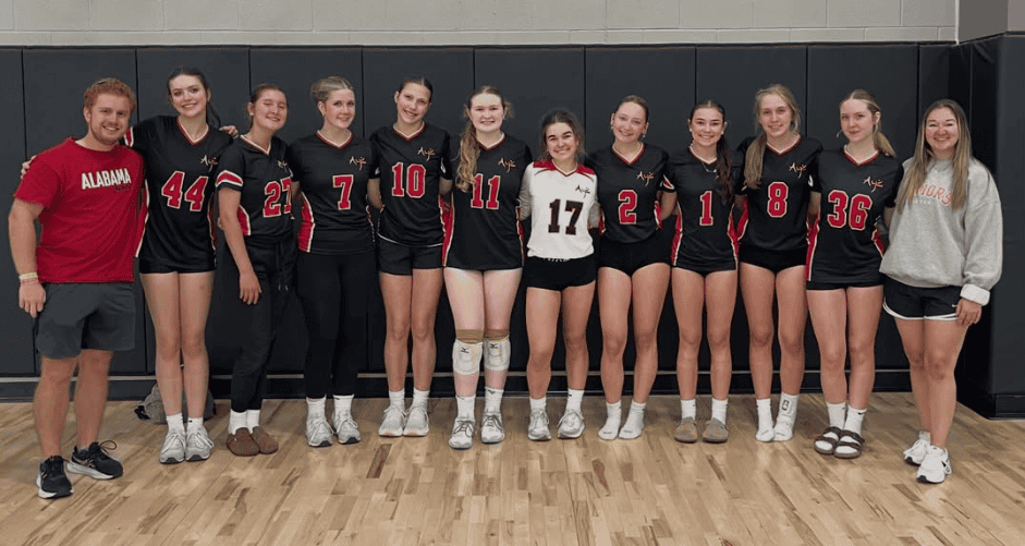 Alabama Juniors volleyball team posing together in a gym after a match
