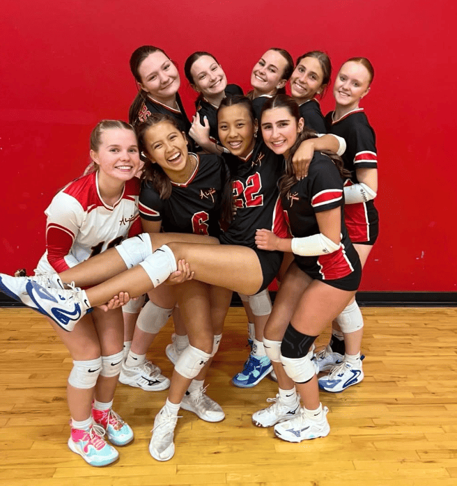 Alabama Juniors Volleyball Club players posing together in volleyball uniforms on a gym court